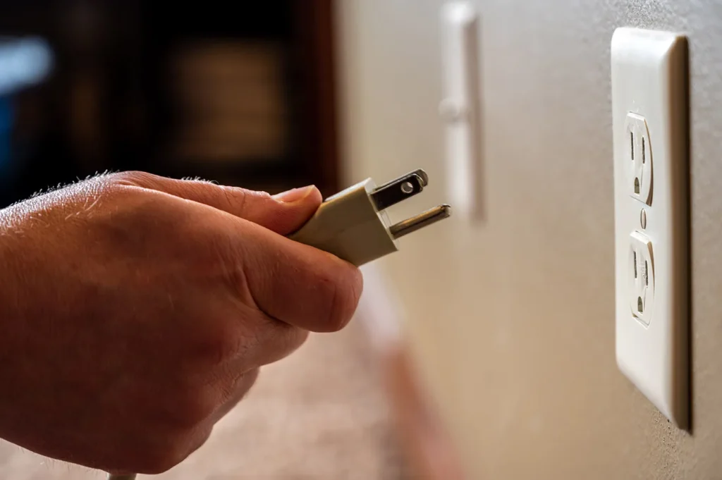 Person unplugging TV power cord.