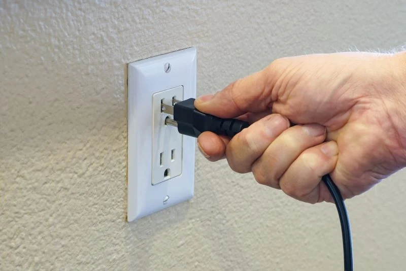 Hand checking the power cord connection on an Onn TV.