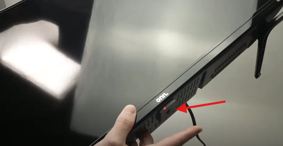 Arrow pointing to the power button on an Onn TV.