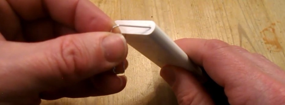 Opening the battery tray on the white Apple Remote