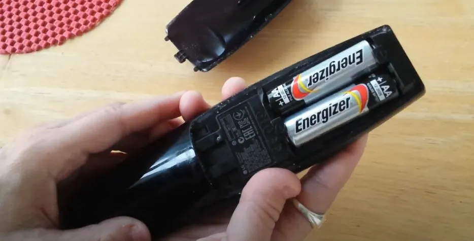 Person inserting batteries into LG Magic Remote